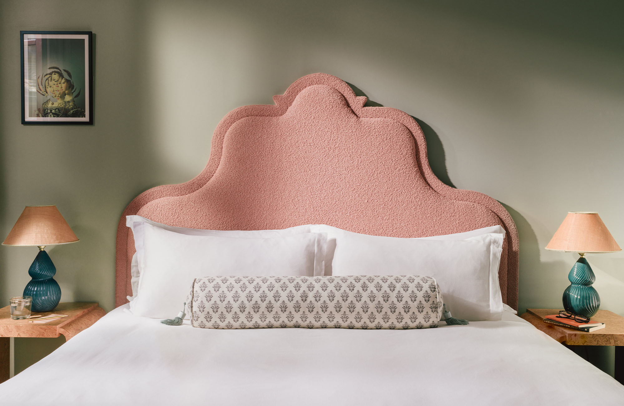 View of a soft pink double-bed headboard with a bedside table on each side.