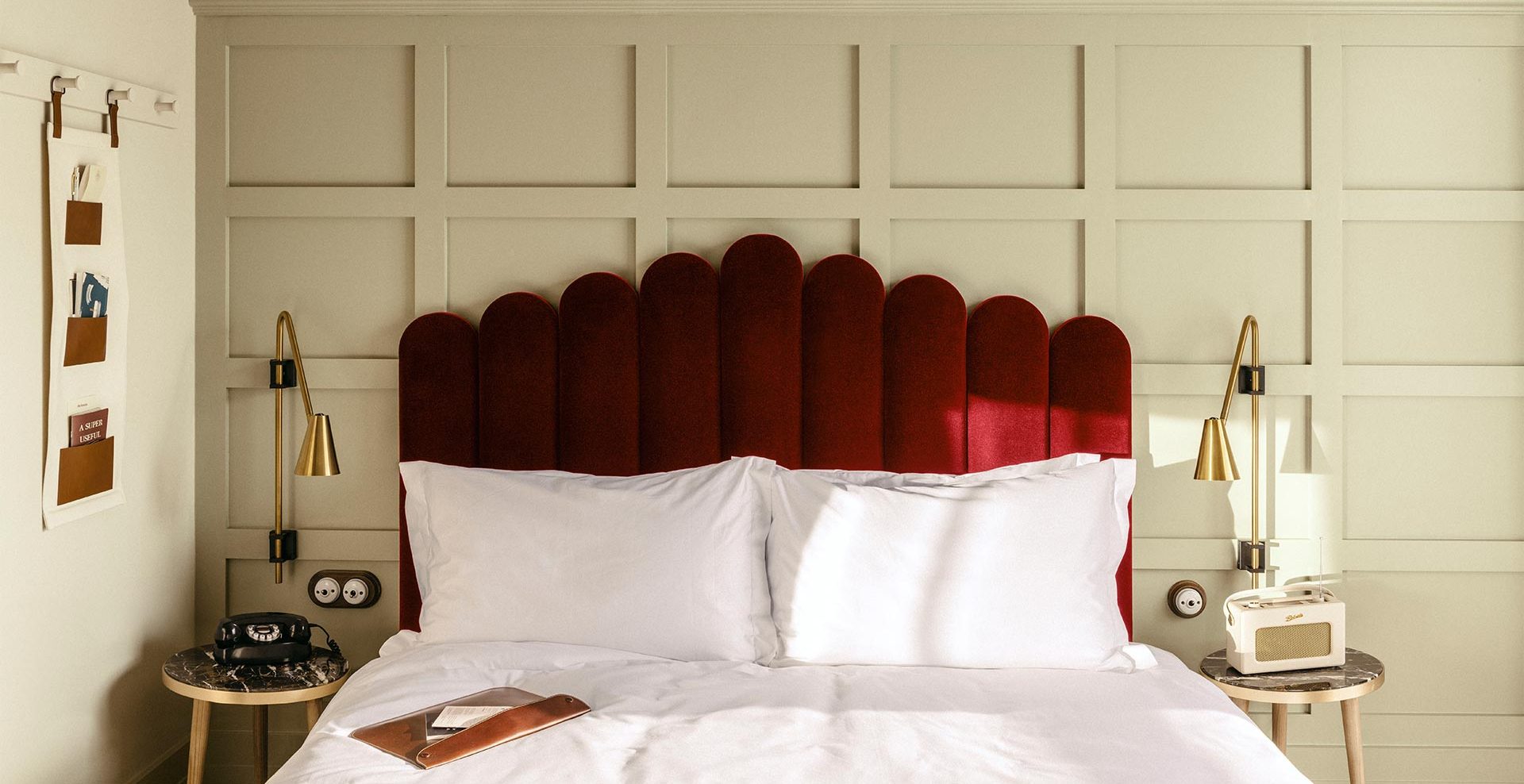 Large red velvet headboard with bedside table and art on the wall.