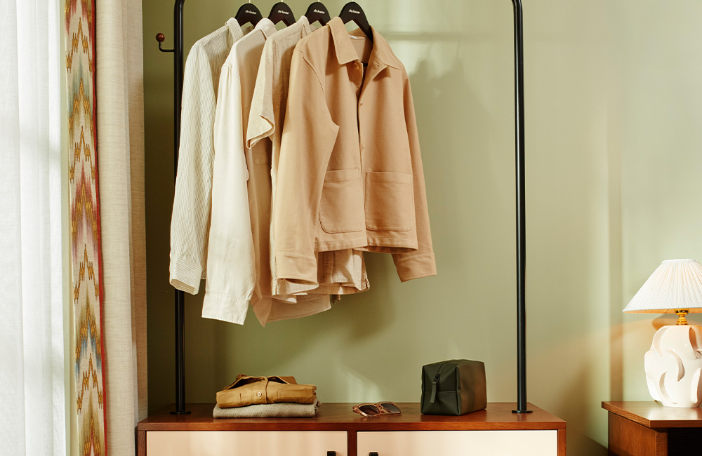 Open wardrobe with hanging space and bottom drawers, positioned next to a large window that fills the room with natural light.